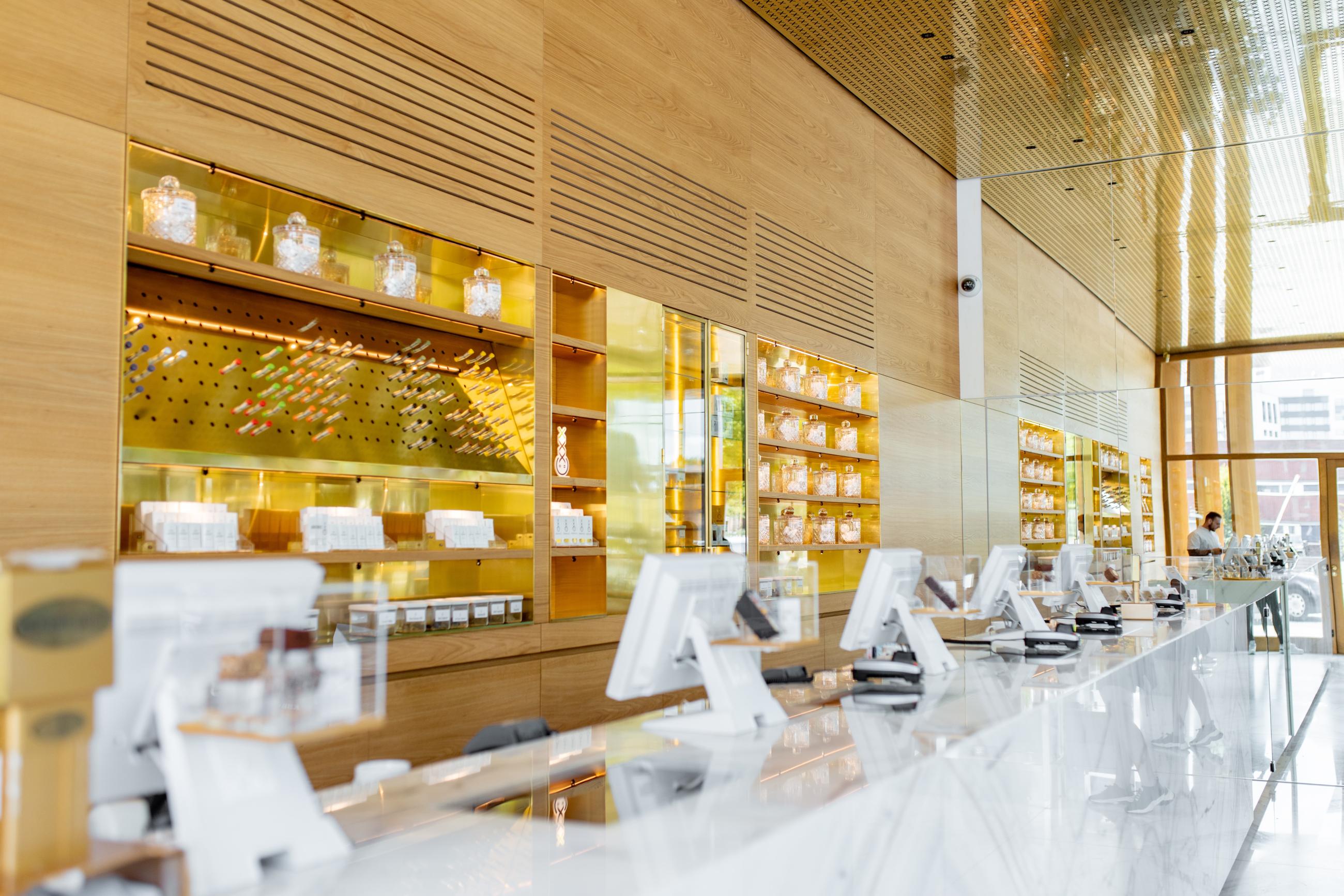 Interior of medical cannabis dispensary with gold wall displaying marijuana product selection